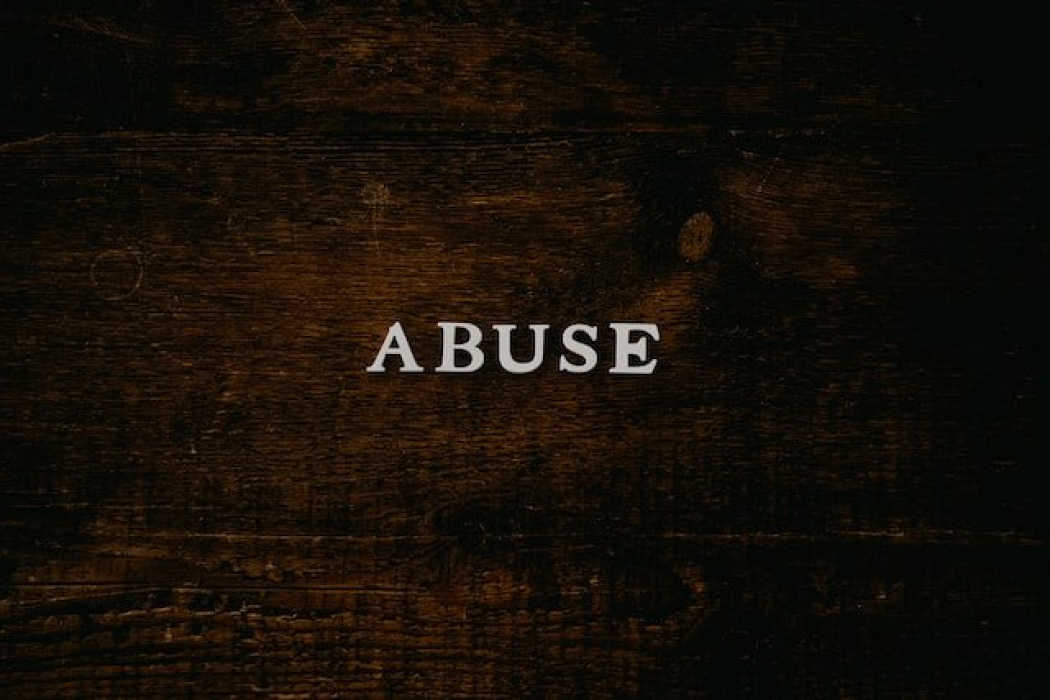 Text "ABUSE" on a dark wooden background, emphasizing themes of abuse law and legal justice related to the Spedding v State of New South Wales case.