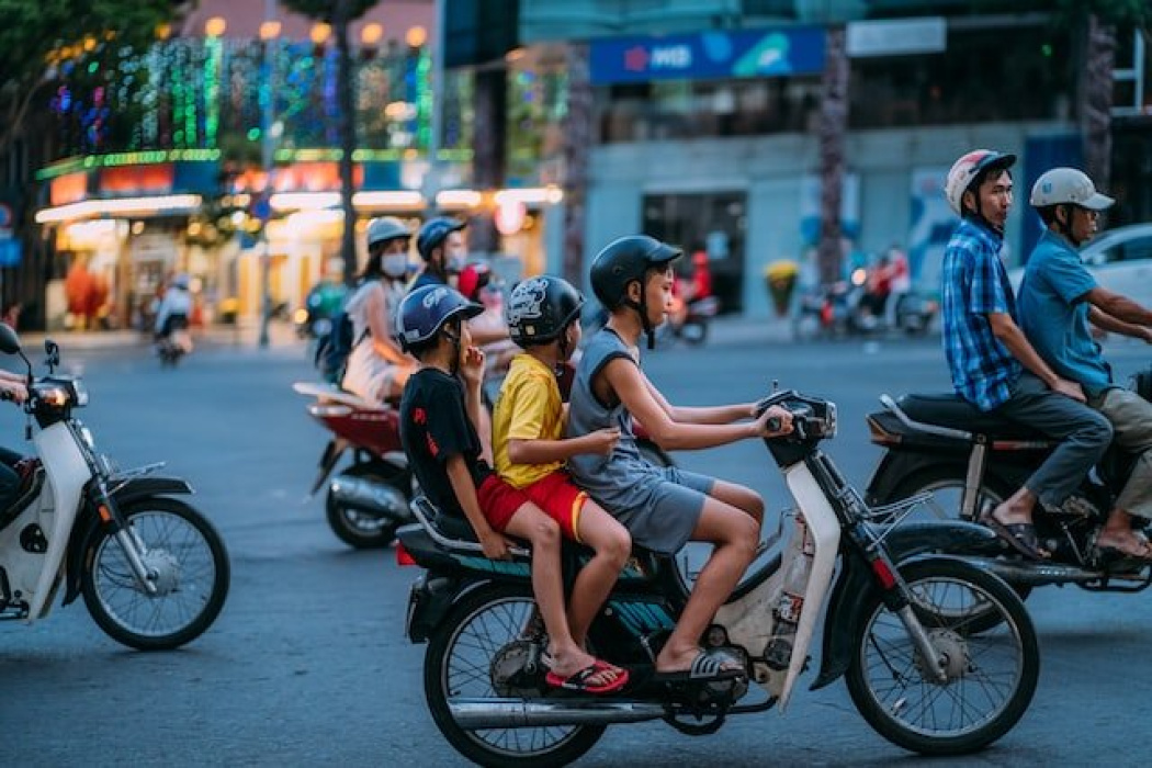 Children riding a motorcycle in a busy street, showcasing urban traffic in Queensland, relevant to personal injury claims and motor vehicle accidents.